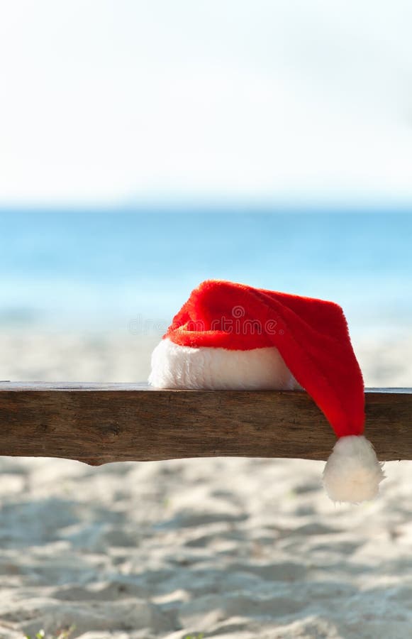 Red Santa s hat on wooden bench on the beach