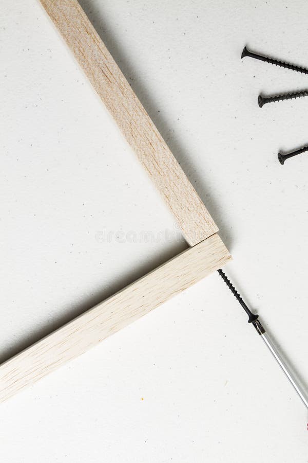 Red screwdriver joining two wooden sticks with black screw on a white background