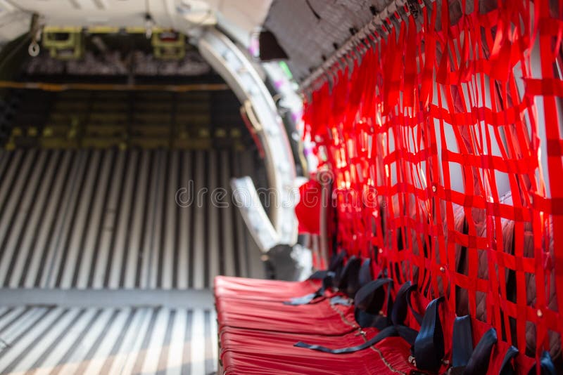 red seat with seatbelt for paratrooper or airborn forces in military transport aircraft cabin