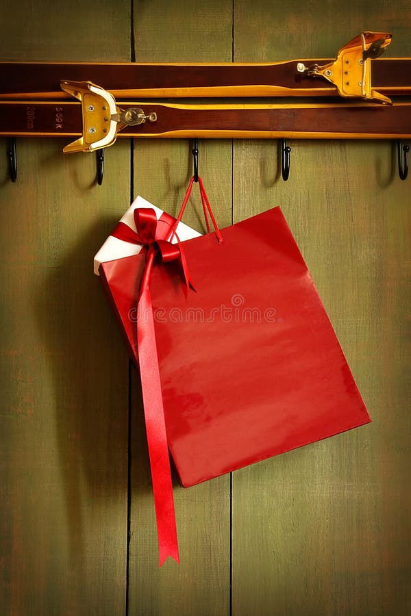 Red shopping bag hanging on hook with green wood background