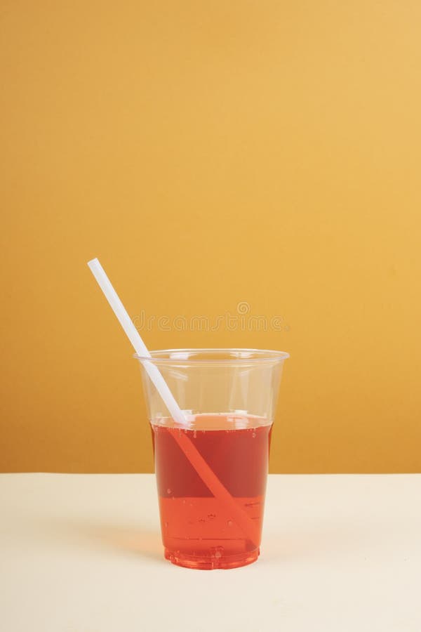 Red Sparkling Water in Plastic Cup with Straw on Table Stock Photo