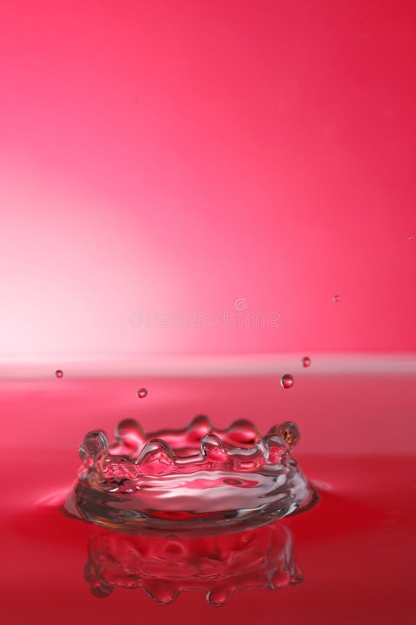 Splashing water droplet over red background, high speed photography. Splashing water droplet over red background, high speed photography.