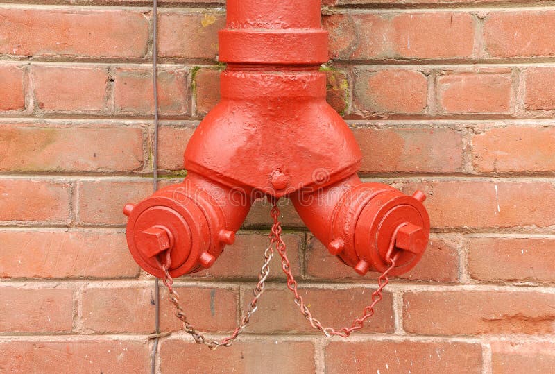 Red Standpipe Against Brick