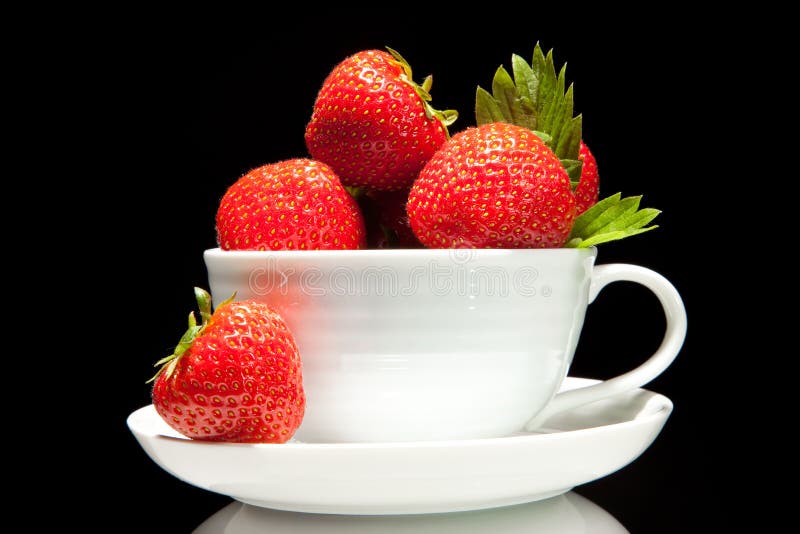 Fresh red strawberry in white cup on a black background