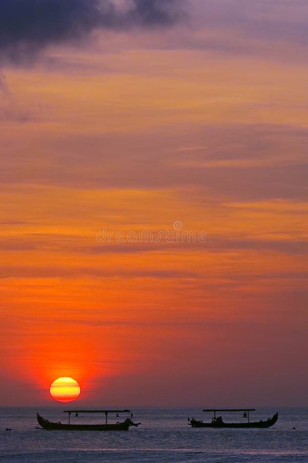 Red sun sunset with fisherman`s boats silhouettes, Kuta beach, Bali
