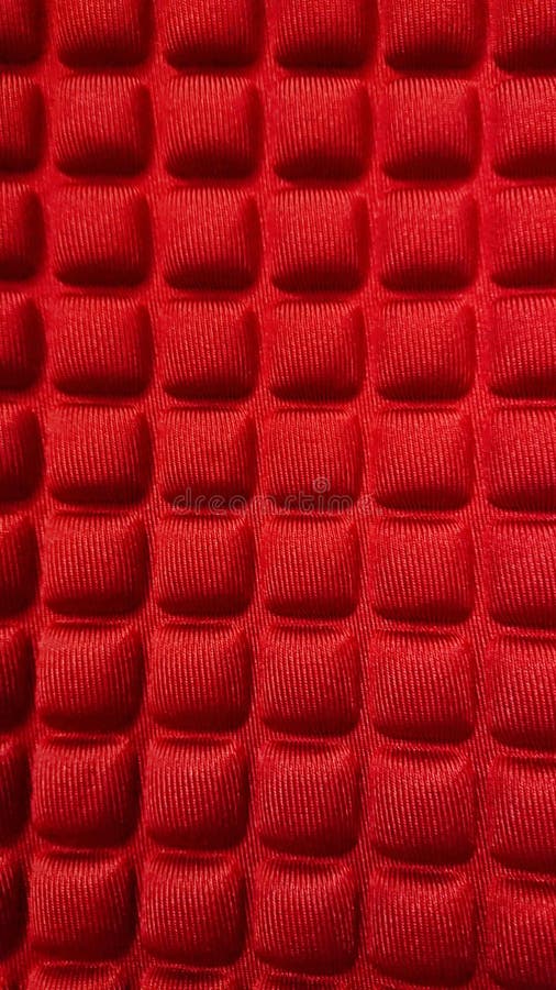 Red textured fabric close-up. Close-up of red fabric with a repetitive square pattern. The geometric design creates a unique, tactile texture, ideal for backgrounds, textiles, or fashion-related themes