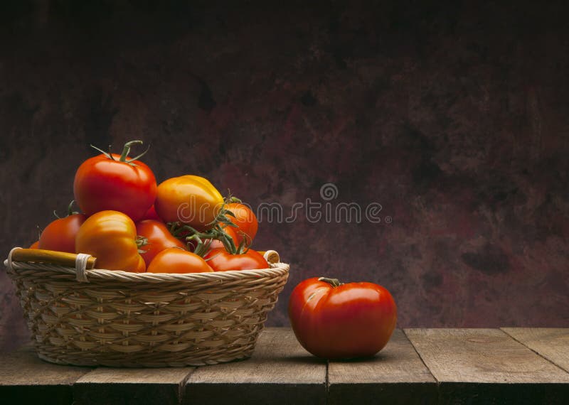 Red tomatoes in basket on dark background