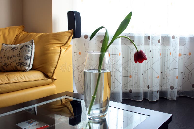 Red tulips on a table of glass in bright living ro