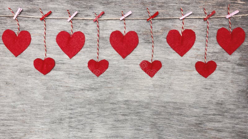 Red Valentine`s love hearts on natural cord and pink pins hanging on rustic driftwood texture background, copy space