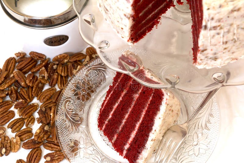 Red Velvet Cake and Pecans. Slice of red velvet cake and pecans with sugar canister in background. Slice is removed from whole cake which is in background. Fork royalty free stock image