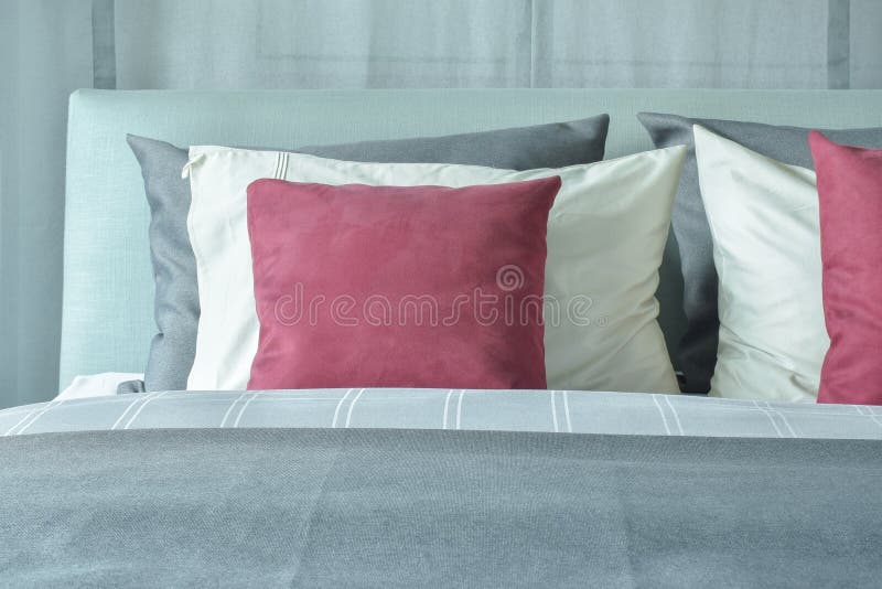 Red Velvet Pillows with White and Gray Pillows Setting on Bed Stock