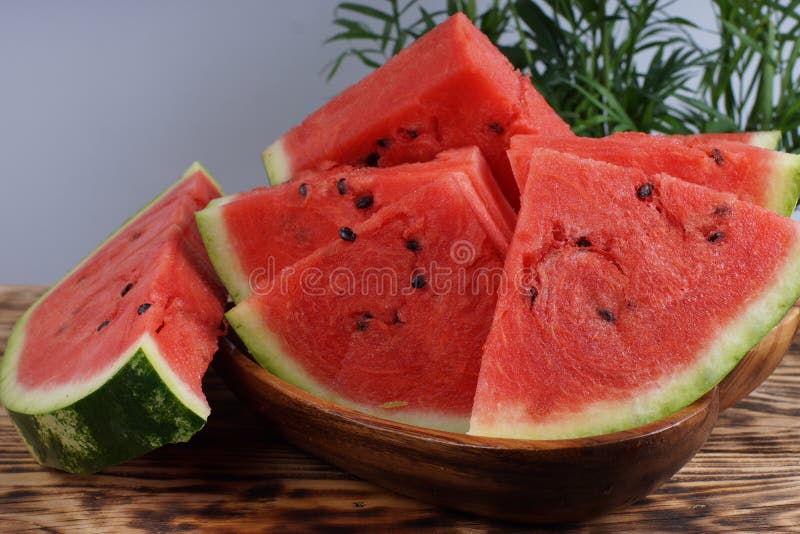 Red watermelon, cut in triangular pieces with green palm leaves in the background. Triangular cut watermelon stock images, royalty-free photos and pictures