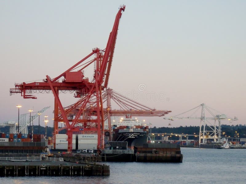 Red and White Cranes unloaded cargo at dusk