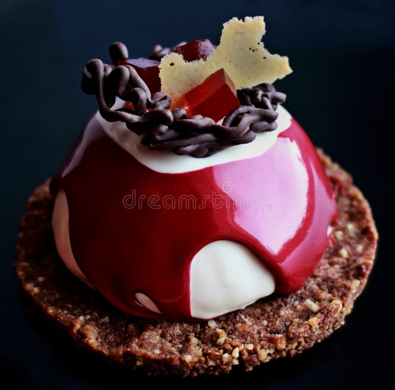 Red and white dessert with chocolate decoration, red jelly and cookie base