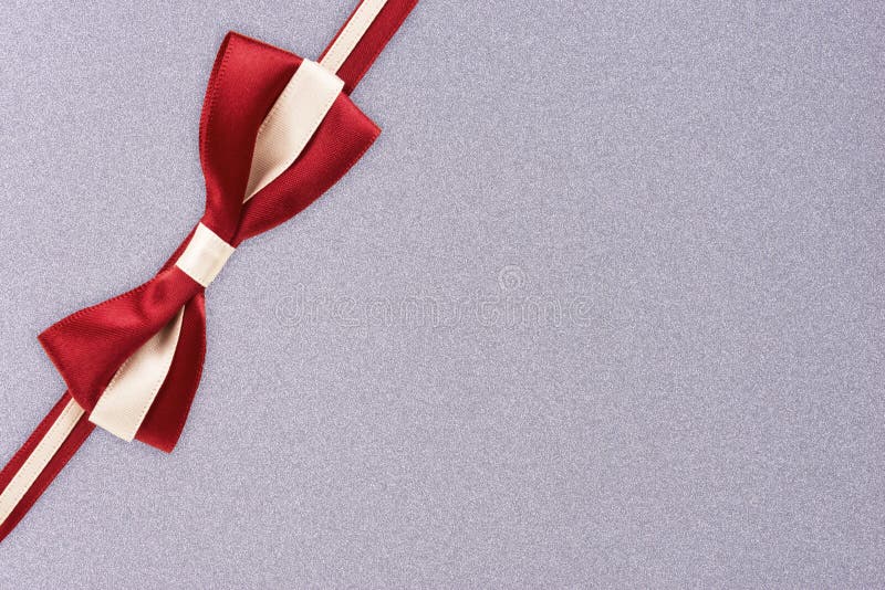 Red and white gift ribbon on a silver textured pattern background. stock photo