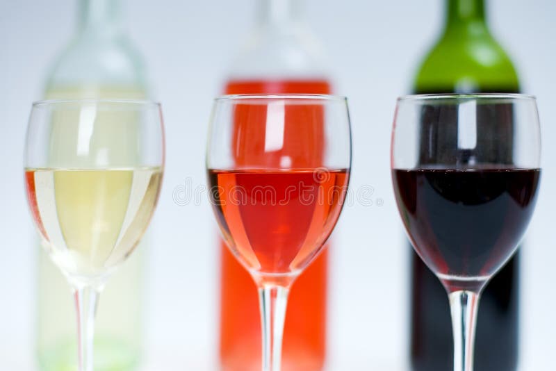 Red, white and rose wine in glasses with bottles behind