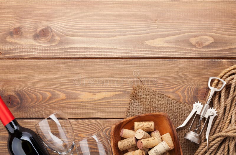 Red wine bottle, glasses, bowl with corks and corkscrew