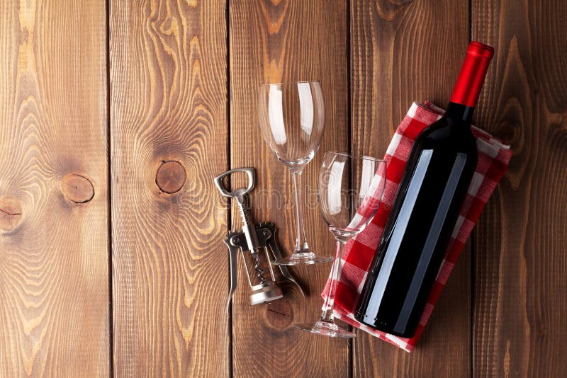 Red wine bottle, glasses and corkscrew on wooden table