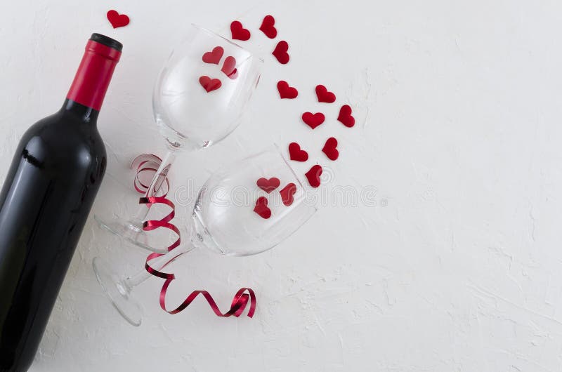 Red wine bottle, with two glasses red hearts and ribbon on white background, top view. Flat lay