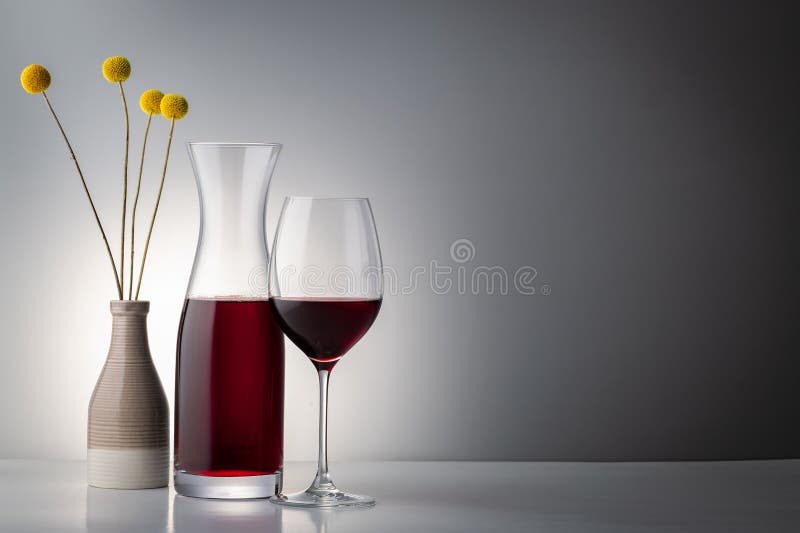 Red wine in an elegant glass with vase and flower royalty free stock images