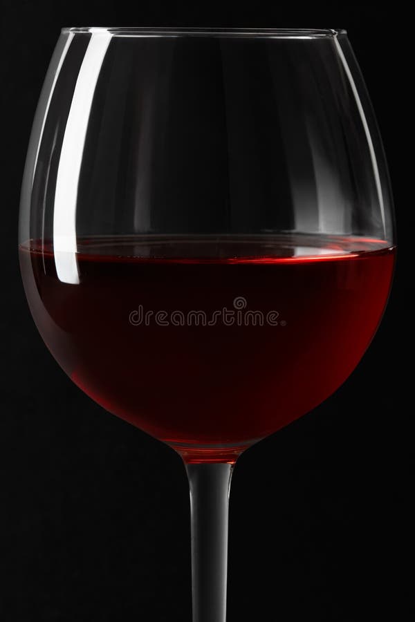 Red wine glass close up on black background