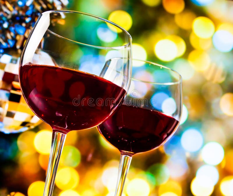 Red wine glasses against colorful bokeh lights and sparkling disco ball background, festive and fun concept