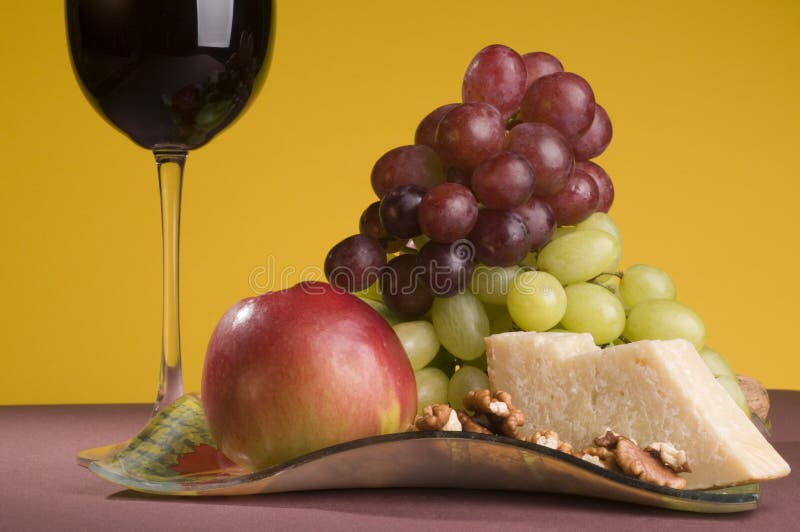 Red wine with grape, apple and cheese on a plate.
