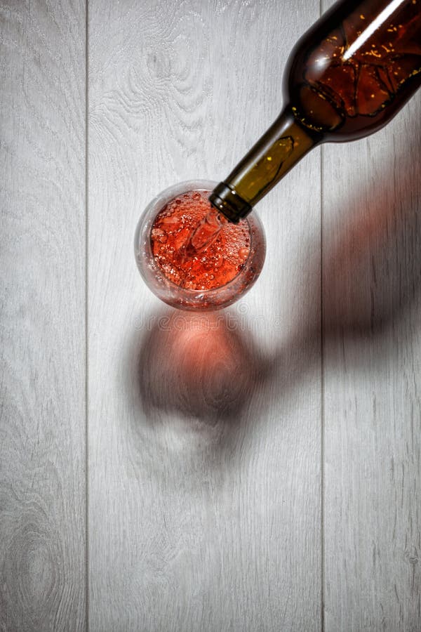 Red wine pouring into glass from bottle on white