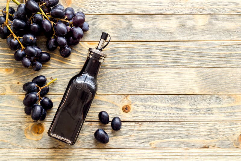 Red Wine Vinegar in Glass Bottle with Bunch of Black Grapes Stock Photo
