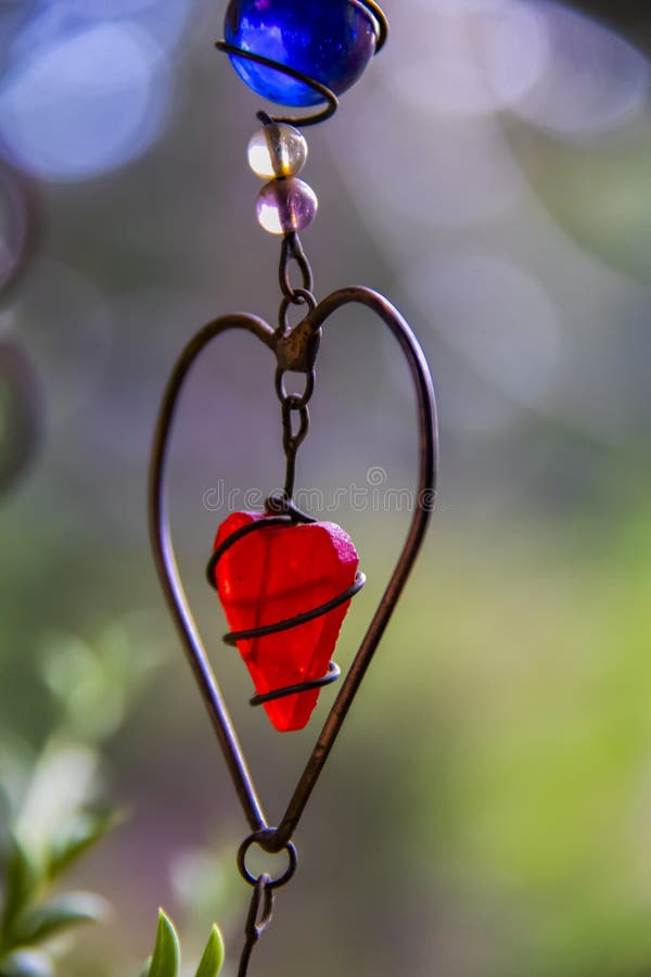 Red wire art heart against green pastel bokeh background