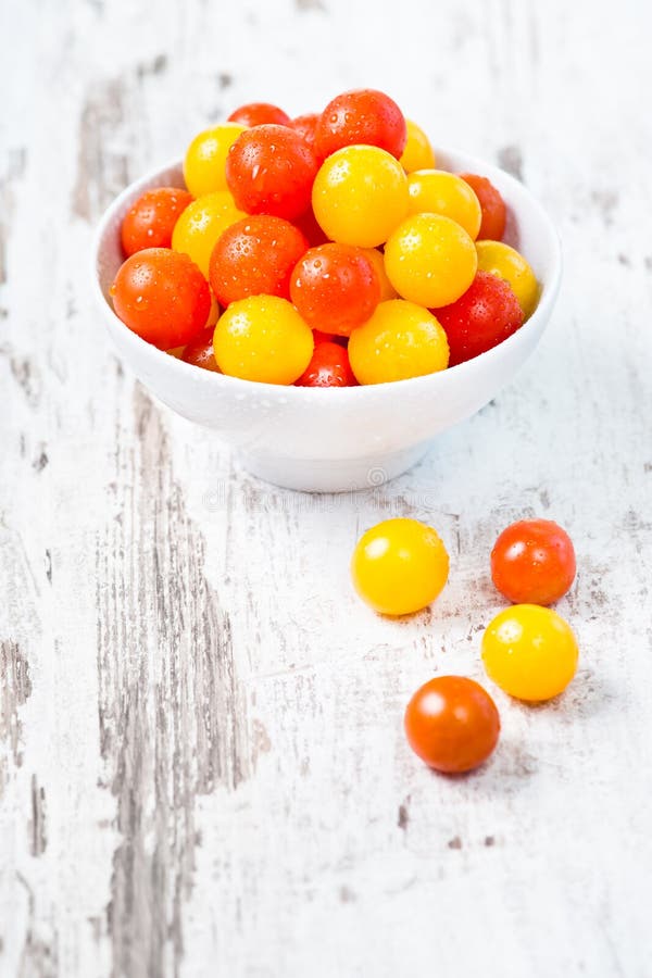 Red and yellow fresh cherry tomatoes in white bowl