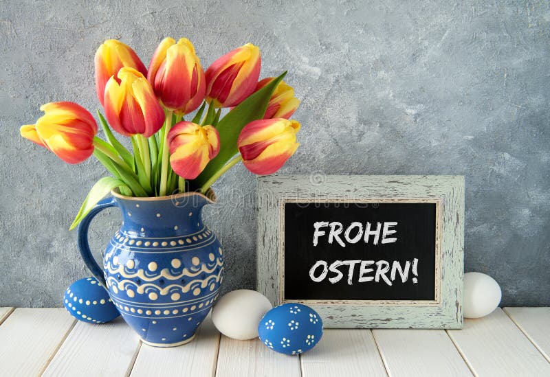 Red-yellow tulips in blue ceramic pitcher with Easter eggs and a royalty free stock photos