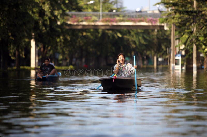 Redactiefoto'svloed in Thailand, een vrouw die in boot drijven en op zijn celtelefoon spreken, Bangkok royalty-vrije stock foto Redactiefoto'svloed in Thailand, een vrouw die in boot drijven en op zijn celtelefoon spreken, Bangkok royalty-vrije stock foto