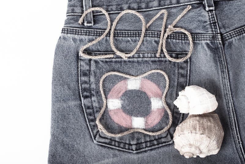 Lifebuoy, rope number 2016 and seashell on jeans pocket background. Toned. Lifebuoy, rope number 2016 and seashell on jeans pocket background. Toned.