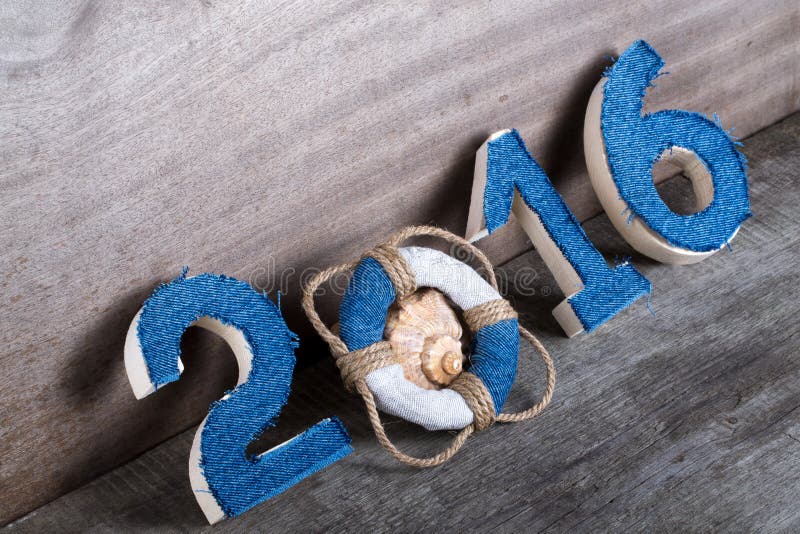 Lifebuoy instead of the digit 0 in the number 2016 and seashell on gray wooden background. Lifebuoy instead of the digit 0 in the number 2016 and seashell on gray wooden background.