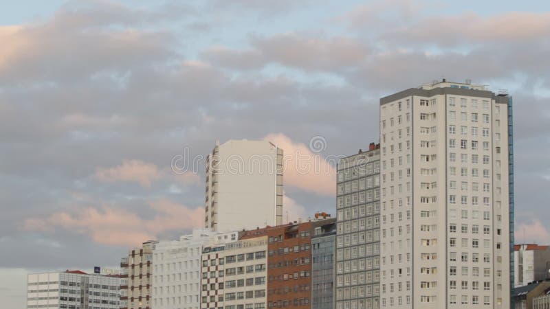 Reddish sunset clouds over buildings in A CoruÃ±a stock footage