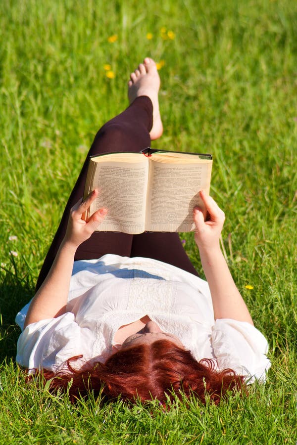 Redhead beautiful girl reading a book in nature
