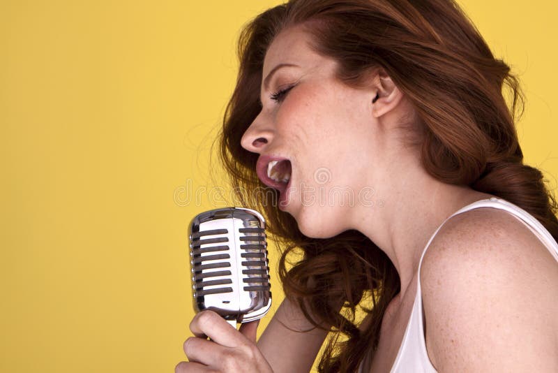 Retro redhead female singer with microphone singing her heart out. Retro redhead female singer with microphone singing her heart out.