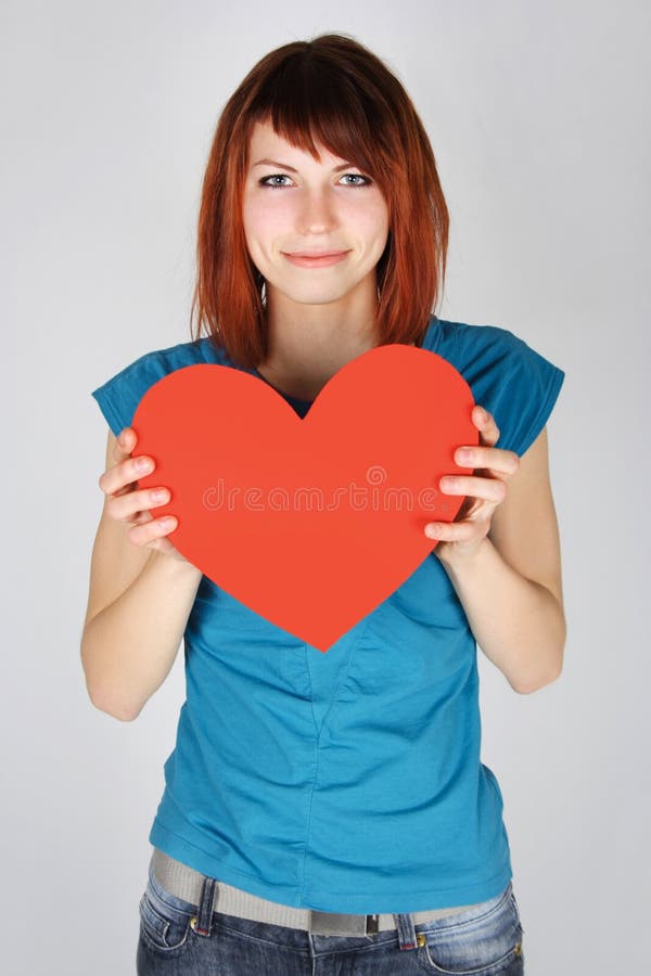 Redhead girl smiling and holding red paper heart