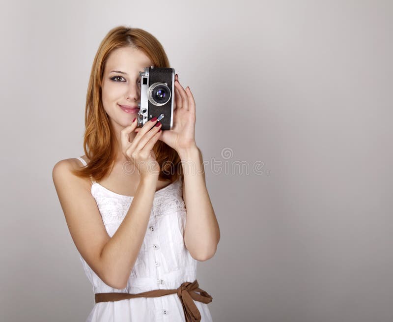 Redhead girl in white dress with vintage camera.