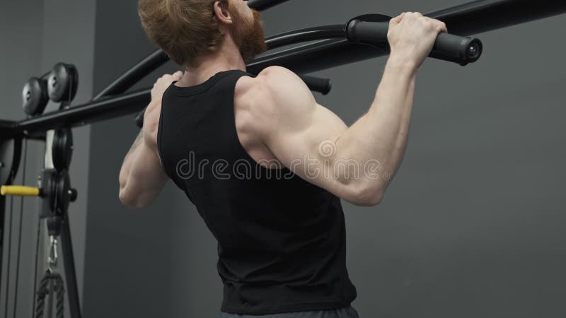 Redhead-man die zich aan de staven trekt tijdens de training in de gym