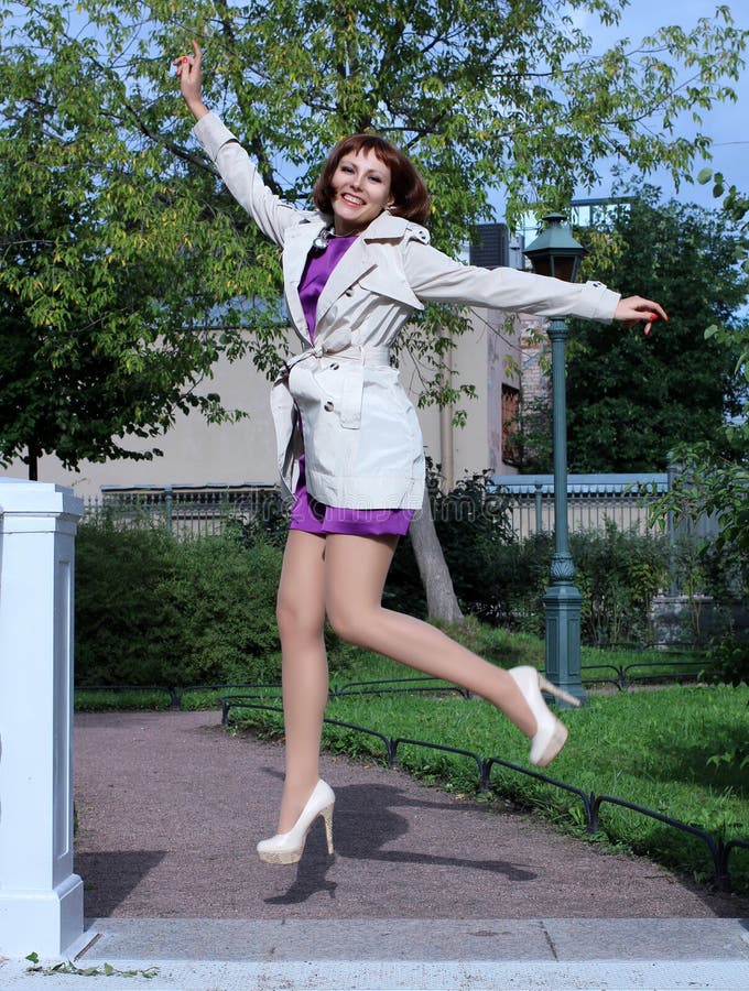 Redhead model in  stockings and violet dress  and white cloak and high heels with pretty face and incredible body posing in nature. Redhead model in  stockings and violet dress  and white cloak and high heels with pretty face and incredible body posing in nature