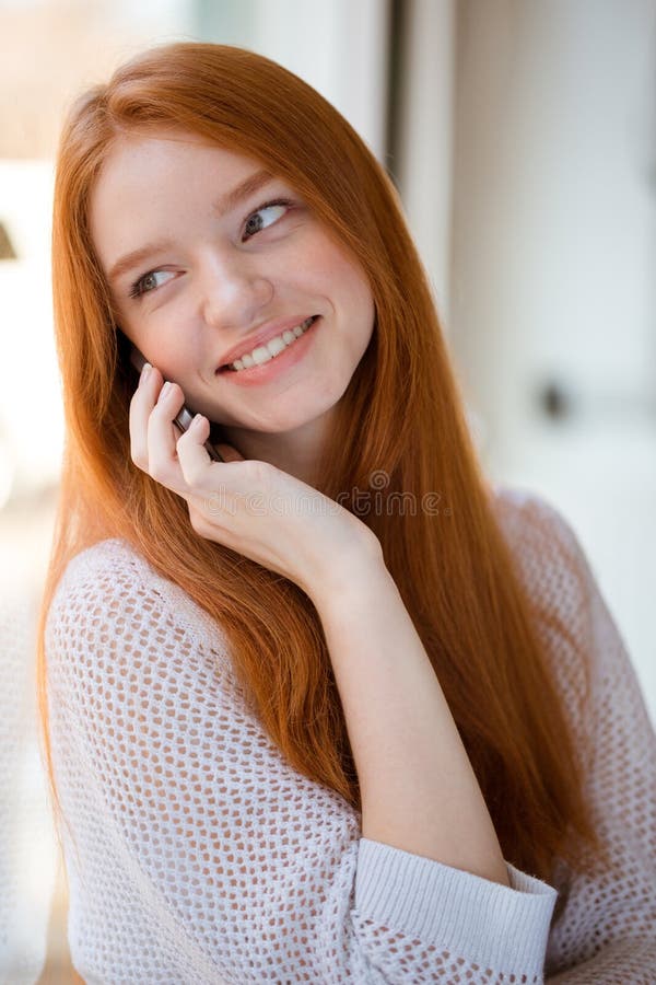 Redhead woman talking on the phone and looking at camera stock image