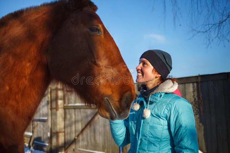 Redhead χαμόγελα κοριτσιών στο κόκκινο άλογο μια ηλιόλουστη χειμερινή ημέρα στοκ εικόνα με δικαίωμα ελεύθερης χρήσης Redhead χαμόγελα κοριτσιών στο κόκκινο άλογο μια ηλιόλουστη χειμερινή ημέρα στοκ εικόνα με δικαίωμα ελεύθερης χρήσης