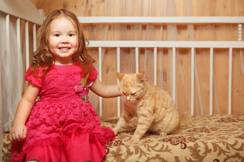 Redhead κορίτσι που κτυπά μια κόκκινη γάτα στοκ φωτογραφία Redhead κορίτσι που κτυπά μια κόκκινη γάτα στοκ φωτογραφία