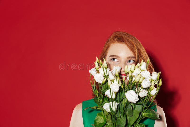 Redhead νέο κορίτσι που καλύπτει το πρόσωπο με τα λουλούδια