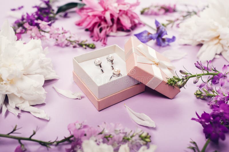 Reeks van pareljuwelen in giftdoos met verse bloemen Zilveren oorringen en ring als heden op purpere achtergrond royalty-vrije stock foto's Reeks van pareljuwelen in giftdoos met verse bloemen Zilveren oorringen en ring als heden op purpere achtergrond royalty-vrije stock foto's