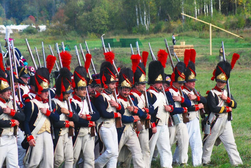 Reenactors dressed as Napoleonic war soldiers march holding guns stock images