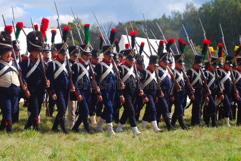 Reenactors dressed as Napoleonic war soldiers march holding guns royalty free stock images