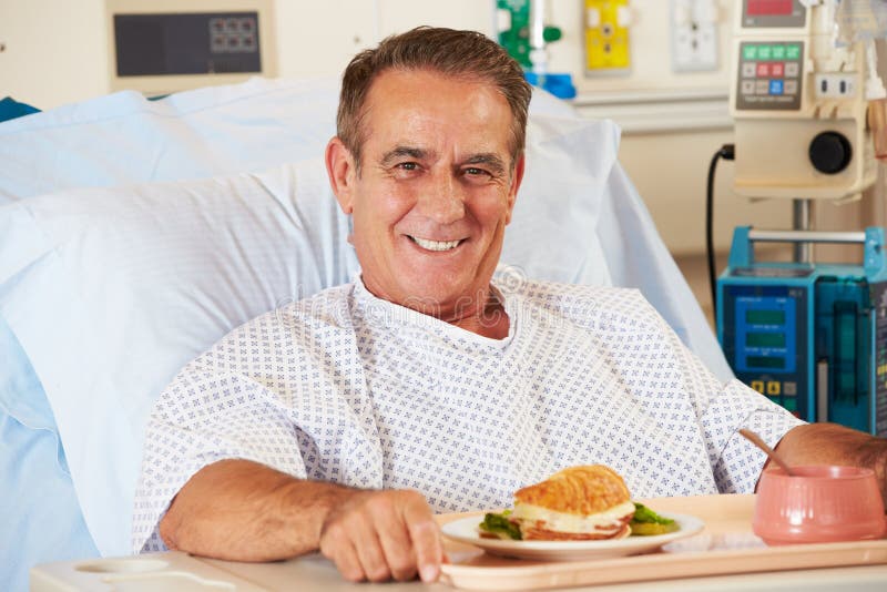 Refeição de apreciação paciente masculina na cama de hospital foto de stock royalty free Refeição de apreciação paciente masculina na cama de hospital foto de stock royalty free
